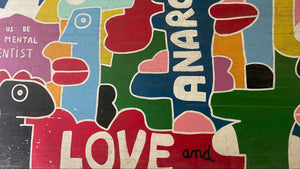 A colorful abstract mural or wall art featuring stylized cartoon-like shapes and large text reading 'ANARCHY' and 'LOVE and' found at The Cable Factory, Helsinki