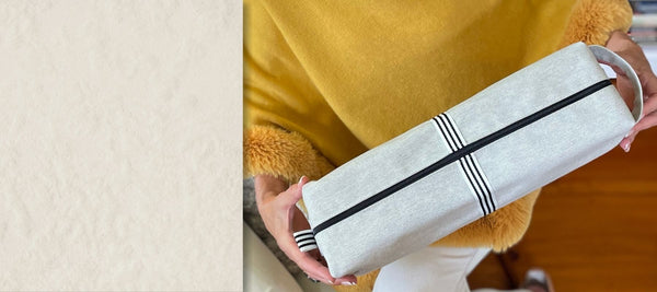 Woman in yellow holding Quiver.love Magnum extra-large wand massager storage pouch for discreet wellness storage