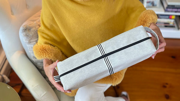 Woman in yellow holding Quiver.love Magnum extra-large wand massager storage pouch in starch denim for discreet wellness storage